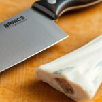 Sharp knife and bone on a wooden cutting board.